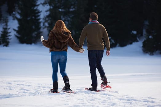 happy young  couple having fun and walking in snow shoes. Romantic winter relaxation scene