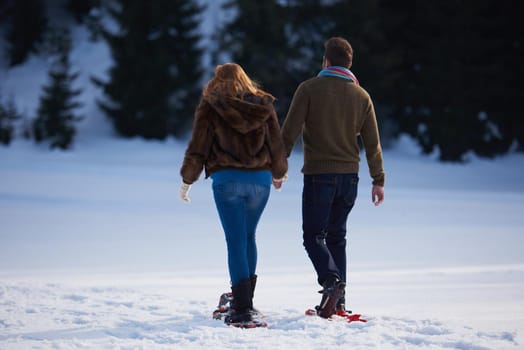 happy young  couple having fun and walking in snow shoes. Romantic winter relaxation scene