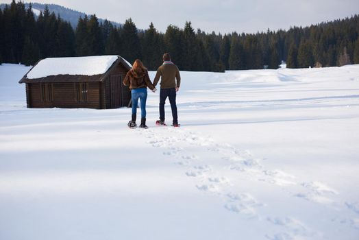 happy young  couple having fun and walking in snow shoes. Romantic winter relaxation scene