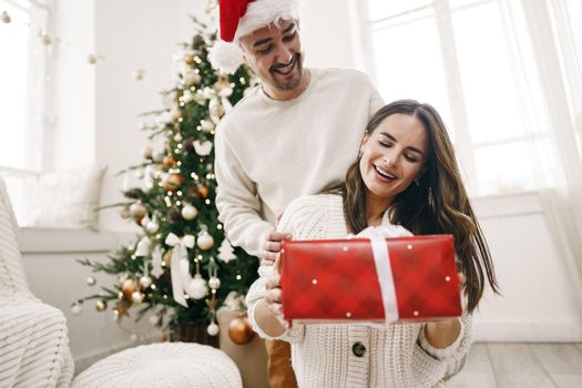 Young cheerful couple in love with present for Christmas, portrait