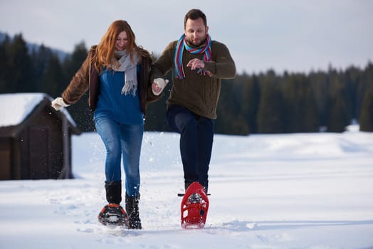 happy young  couple having fun and walking in snow shoes. Romantic winter relaxation scene