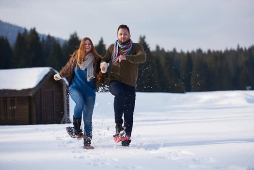 happy young  couple having fun and walking in snow shoes. Romantic winter relaxation scene