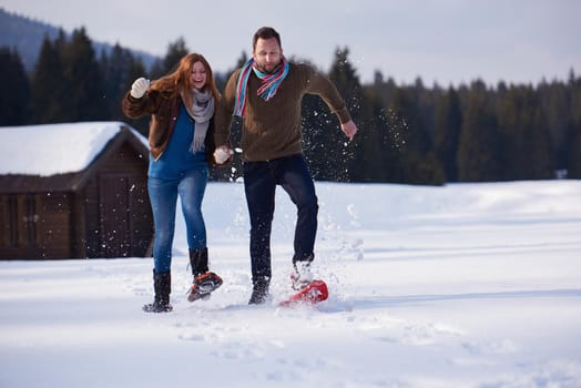 happy young  couple having fun and walking in snow shoes. Romantic winter relaxation scene