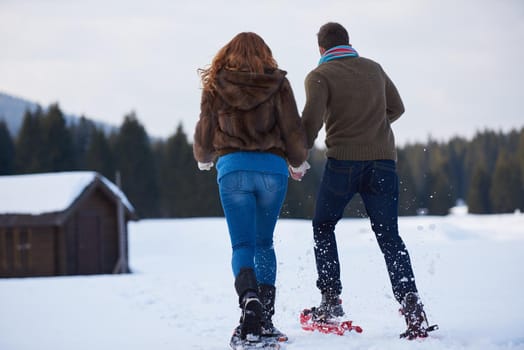 happy young  couple having fun and walking in snow shoes. Romantic winter relaxation scene