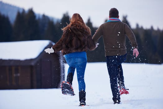 happy young  couple having fun and walking in snow shoes. Romantic winter relaxation scene