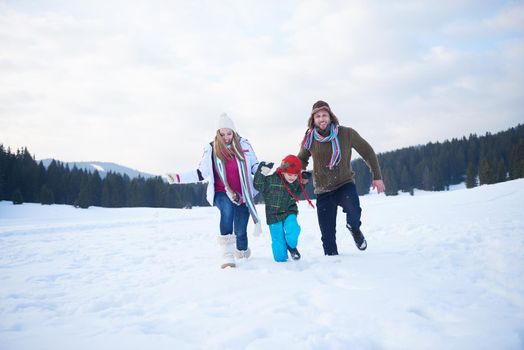 happy young  family playing in fresh snow  at beautiful sunny winter day outdoor in nature