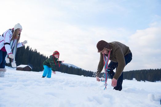 happy young  family playing in fresh snow  at beautiful sunny winter day outdoor in nature