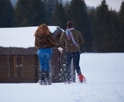 happy young  couple having fun and walking in snow shoes. Romantic winter relaxation scene