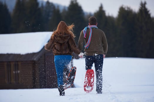 happy young  couple having fun and walking in snow shoes. Romantic winter relaxation scene