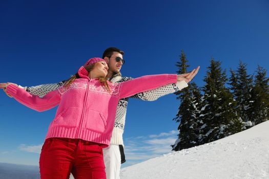 Happy young couple has fun on fresh snow at beautiful winter sunny day on vacation