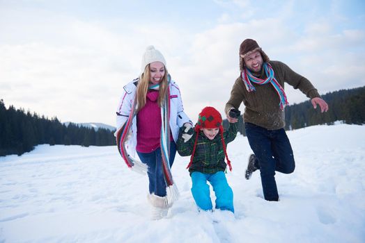 happy young  family playing in fresh snow  at beautiful sunny winter day outdoor in nature