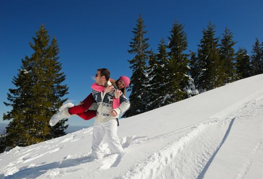 Happy young couple has fun on fresh snow at beautiful winter sunny day on relaxing vacation