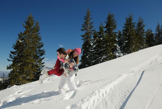 Happy young couple has fun on fresh snow at beautiful winter sunny day on relaxing vacation