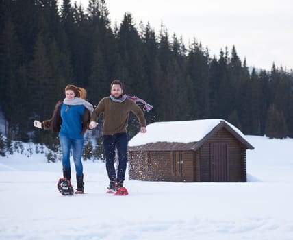 happy young  couple having fun and walking in snow shoes. Romantic winter relaxation scene