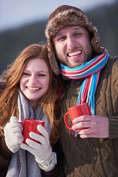 portrait of happy young couple outdoor on winter day drinking warm tea