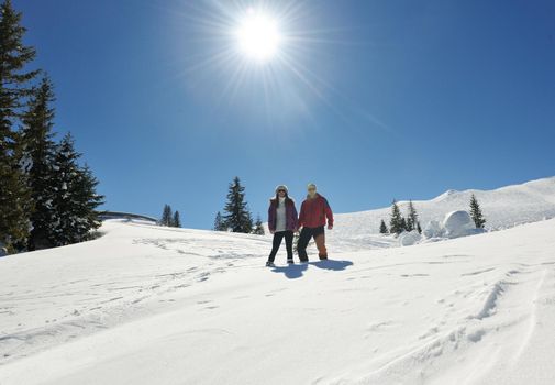 Happy young couple has fun on fresh snow at beautiful winter sunny day on relaxing vacation