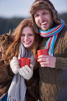 portrait of happy young couple outdoor on winter day drinking warm tea