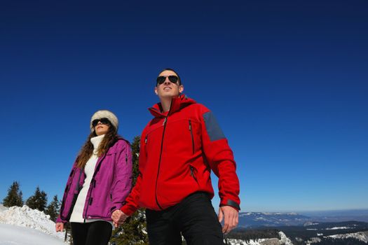 Happy young couple has fun on fresh snow at beautiful winter sunny day on relaxing vacation