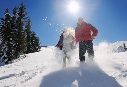 Happy young couple has fun on fresh snow at beautiful winter sunny day on relaxing vacation