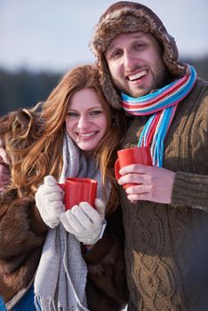 portrait of happy young couple outdoor on winter day drinking warm tea