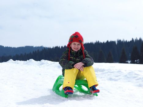 happy young boy have fun on winter vacatioin, sledding children on fresh snow at sunny day outdoor in nature