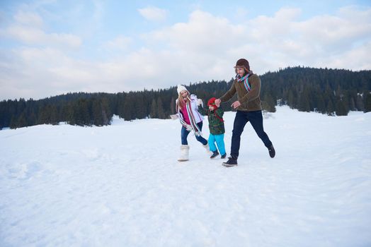 happy young  family playing in fresh snow  at beautiful sunny winter day outdoor in nature