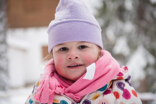 portrait of happy smiling little girl outdoors, having fun and playing on fresh snow on snowy  winter day