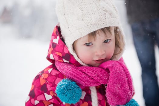 portrait of happy smiling little girl outdoors, having fun and playing on fresh snow on snowy  winter day