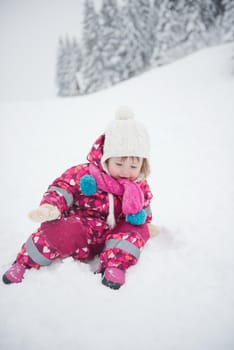 portrait of happy smiling little girl outdoors, having fun and playing on fresh snow on snowy  winter day