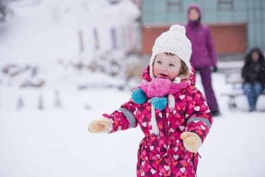 portrait of happy smiling little girl outdoors, having fun and playing on fresh snow on snowy  winter day