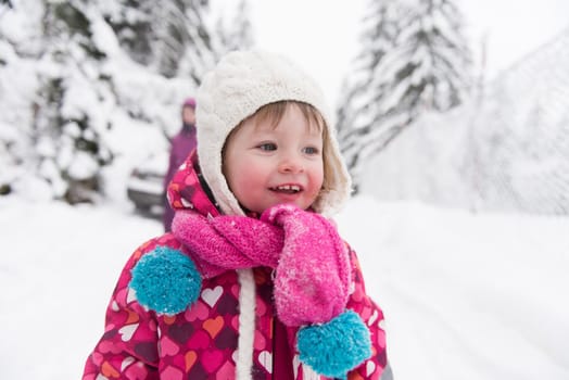 portrait of happy smiling little girl child outdoors having fun and playing on snowy winter day