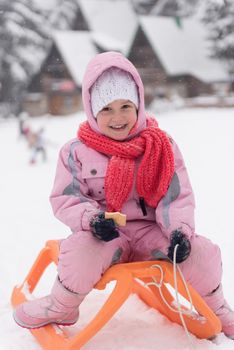 portrait of cute little girl child sitting on sledges at winter day with fresh snow,  eat cookies and have break