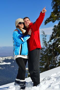 Happy young couple has fun on fresh snow at beautiful winter sunny day on vacation