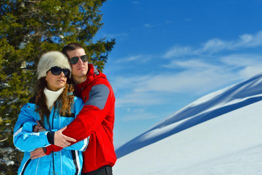 Happy young couple has fun on fresh snow at beautiful winter sunny day on relaxing vacation