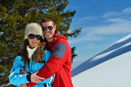 Happy young couple has fun on fresh snow at beautiful winter sunny day on relaxing vacation