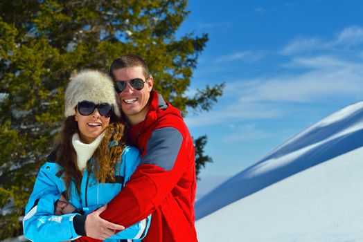 Happy young couple has fun on fresh snow at beautiful winter sunny day on relaxing vacation