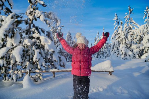 little girl having fun  throwing fresh snow at beautiful sunny winter day