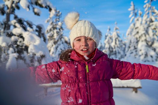 little girl having fun  throwing fresh snow at beautiful sunny winter day