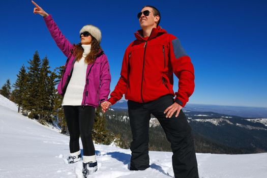 Happy young couple has fun on fresh snow at beautiful winter sunny day on vacation