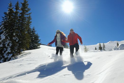 Happy young couple has fun on fresh snow at beautiful winter sunny day on relaxing vacation