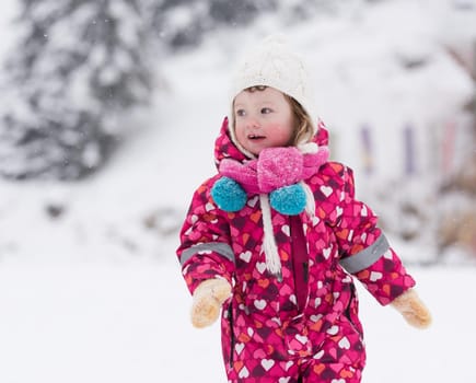 portrait of happy smiling little girl child outdoors having fun and playing on snowy winter day