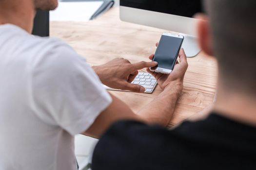 close up. a young man with a smartphone sitting at his Desk. people and technology