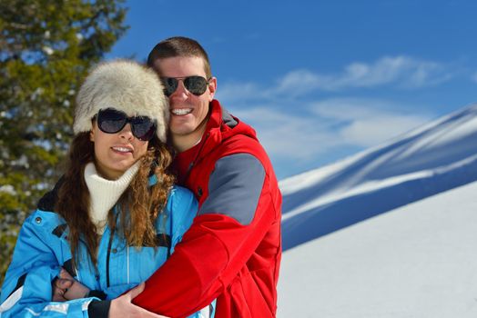 Happy young couple has fun on fresh snow at beautiful winter sunny day on relaxing vacation