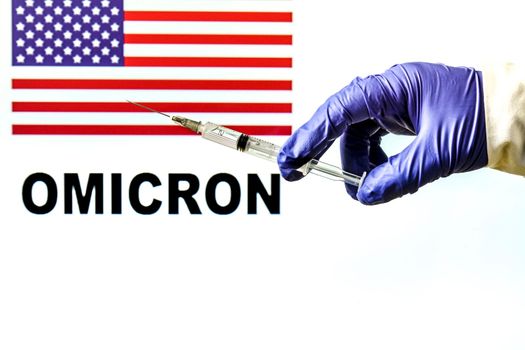 Hand holding syringe with covid vaccine. United States flag and Omicron covid variant word written in the background