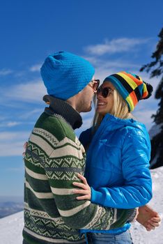 Happy young couple has fun on fresh snow at beautiful winter sunny day on vacation