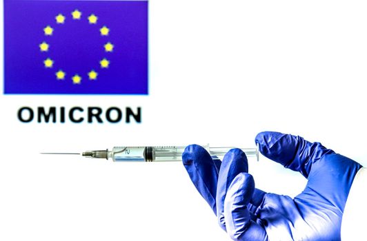 Hand holding syringe with covid vaccine. European flag and Omicron covid variant word written in the background
