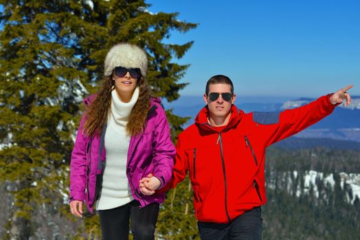 Happy young couple has fun on fresh snow at beautiful winter sunny day on vacation