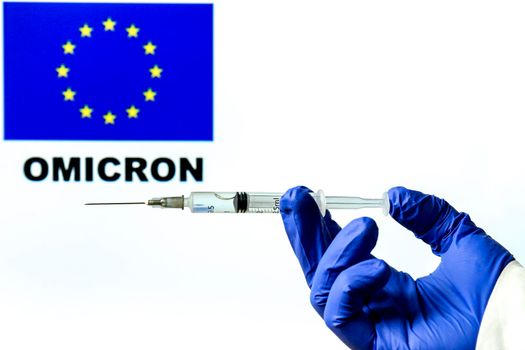 Hand holding syringe with covid vaccine. European flag and Omicron covid variant word written in the background