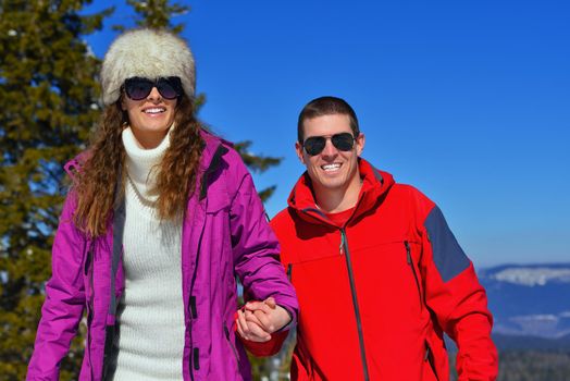 Happy young couple has fun on fresh snow at beautiful winter sunny day on vacation