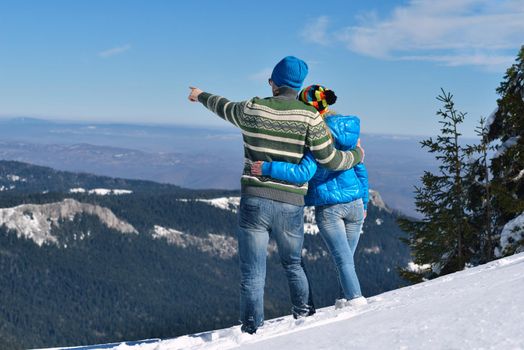 Happy young couple has fun on fresh snow at beautiful winter sunny day on vacation